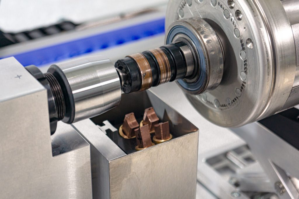 Slip ring on a rotor shaft on the test bench, with the carbon brush holder below it.